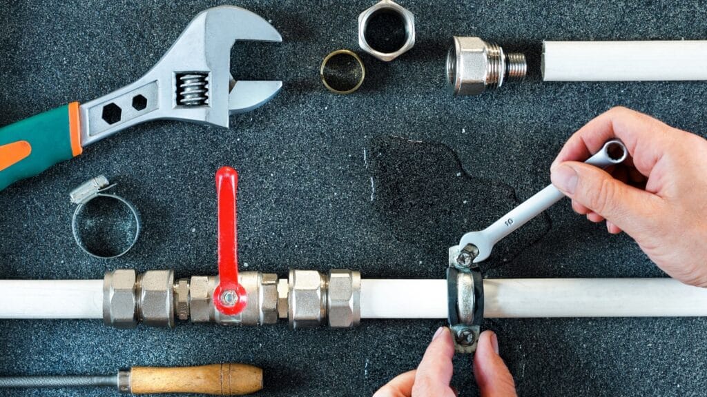 Plumber repairing a pipe valve with an adjustable wrench in North Fort Myers