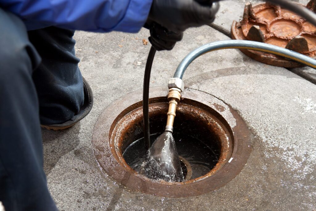 Plumber hydro jetting a sewer line through a manhole in North Fort Myers