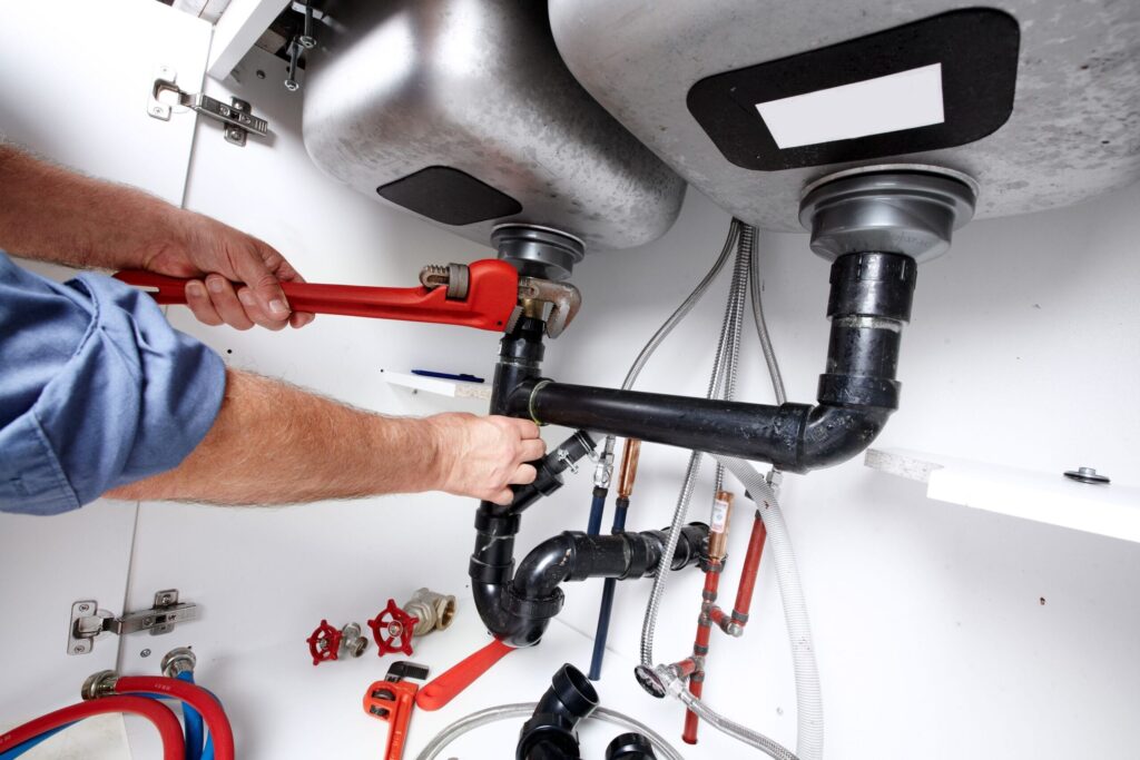 Plumber repairing drain pipes beneath a kitchen sink in North Fort Myers