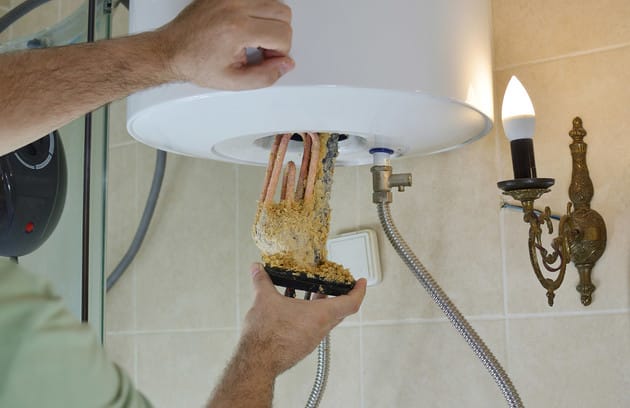 Technician removing mineral buildup from a water heater in North Fort Myers